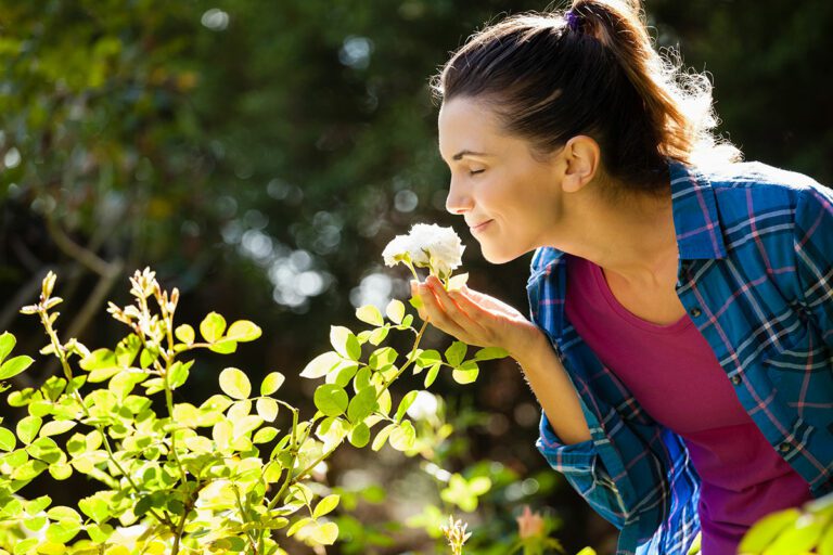 Smiling woman smelling rose outdoors